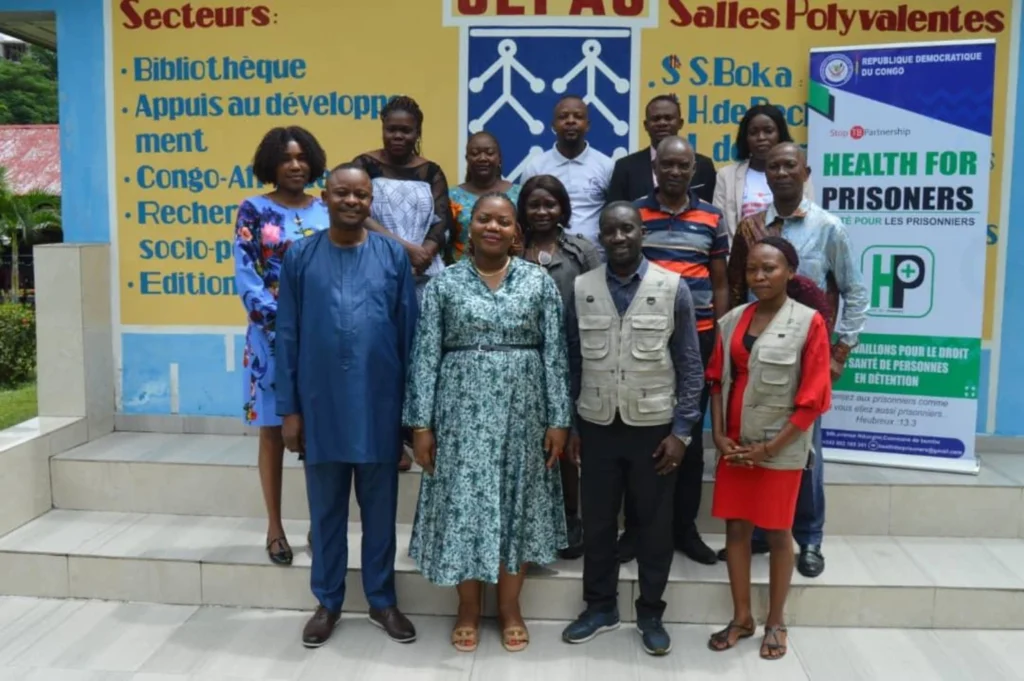 Groupe réuni devant un bâtiment avec une banderole Health For Prisoners